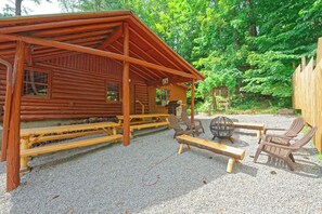 A rustic cabin with a covered patio area, wooden benches, and outdoor seating.