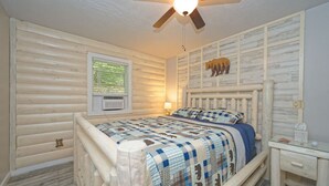 A bedroom with a wooden log wall, a bed with a blue and white checkered bedspread, a ceiling fan, and a window with blinds. - Black Bear Lodge -Spacious 4BR in Prime LG Location! (Lake George)