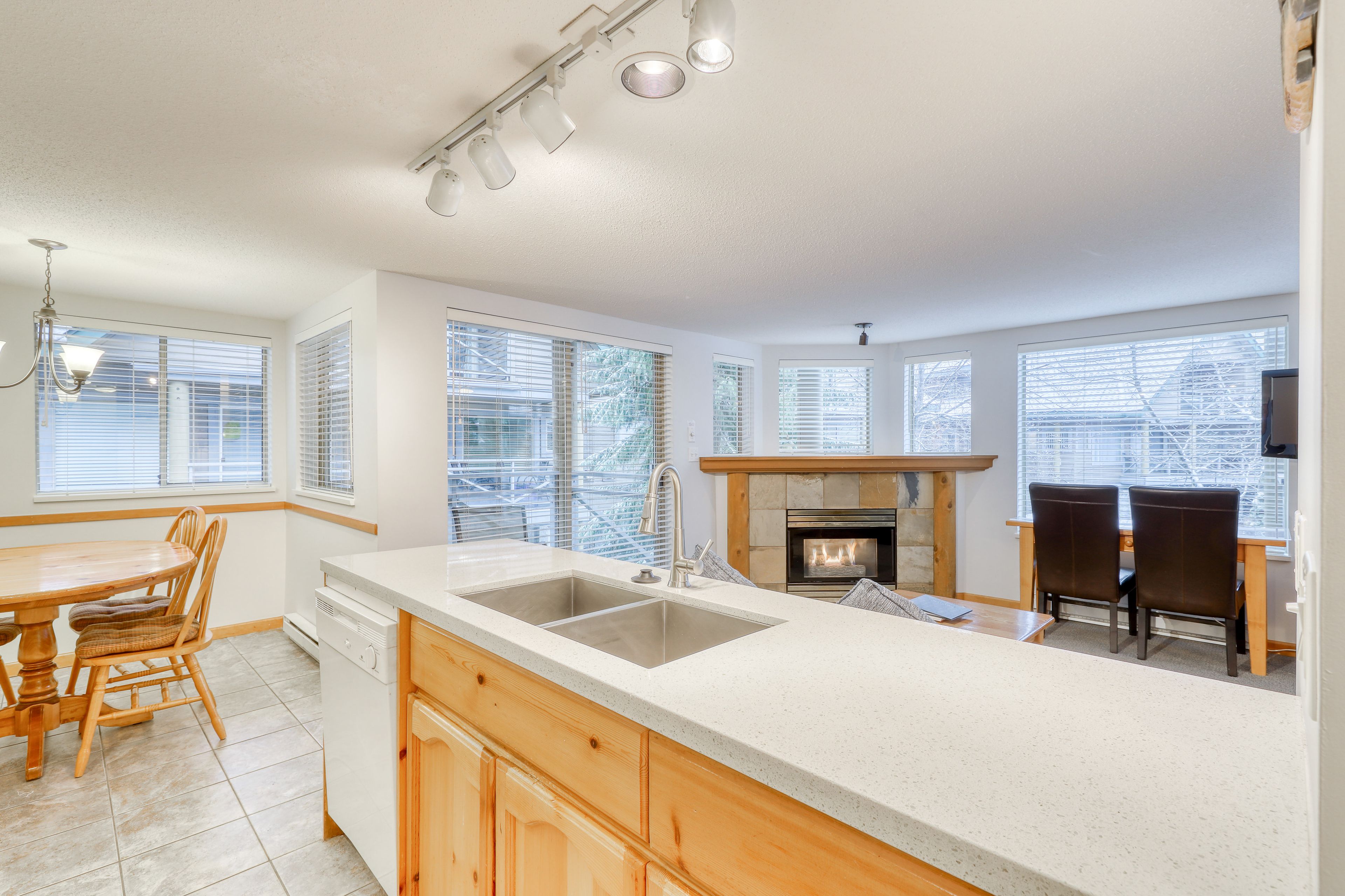 A kitchen with a large island, wooden cabinets, a built-in dishwasher, and a fireplace.