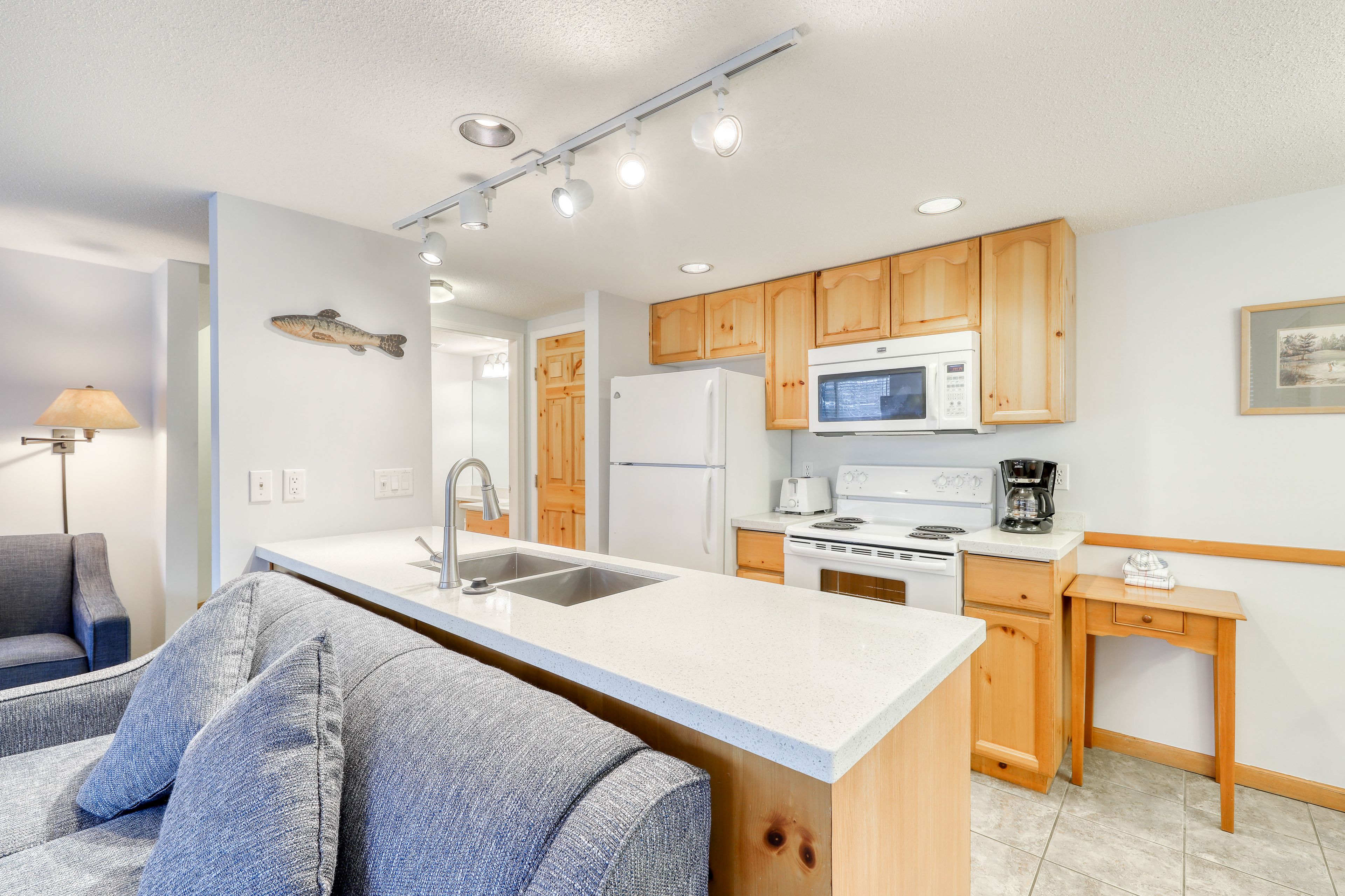 A modern kitchen with wooden cabinets, a white countertop, and a built-in microwave.