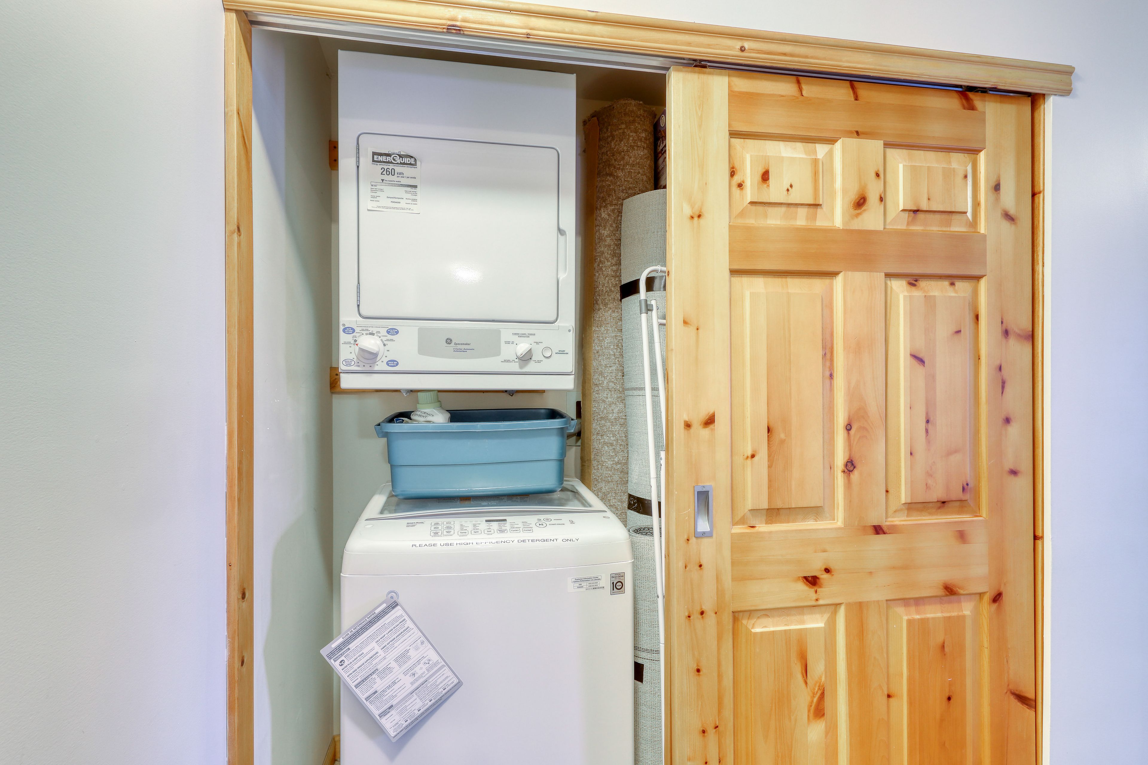 A laundry room with a washing machine and dryer, a wooden door, and a white wall.