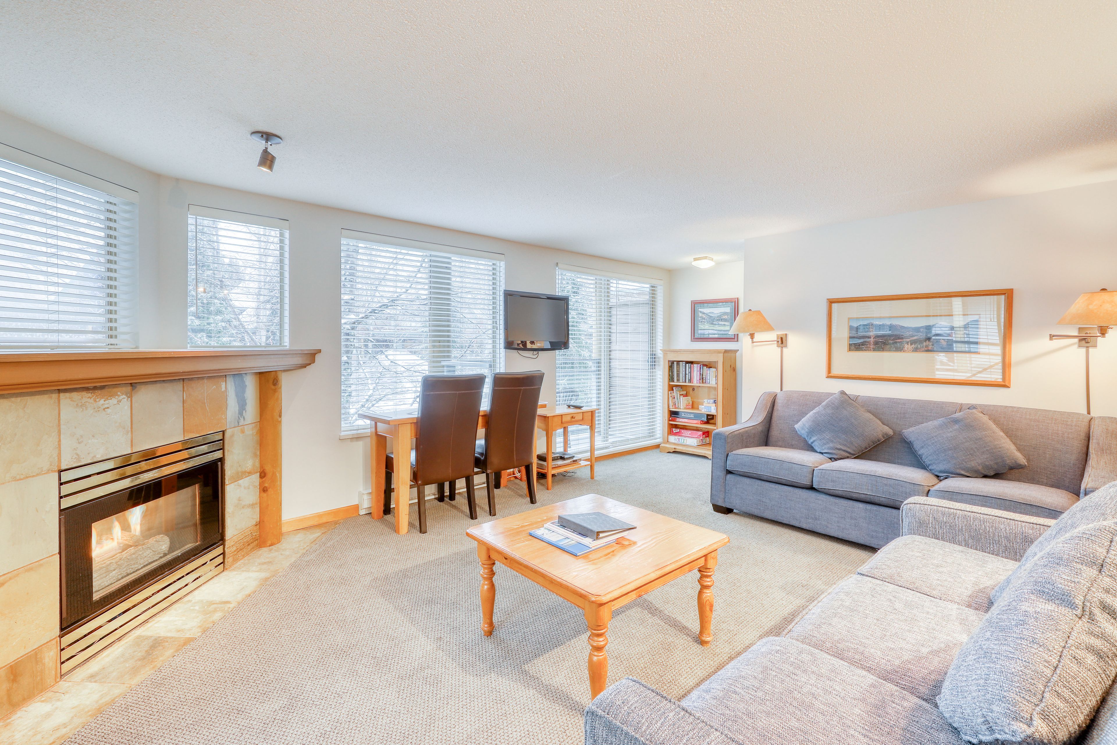 A living room with a fireplace, a sofa, a coffee table, and a bookshelf.