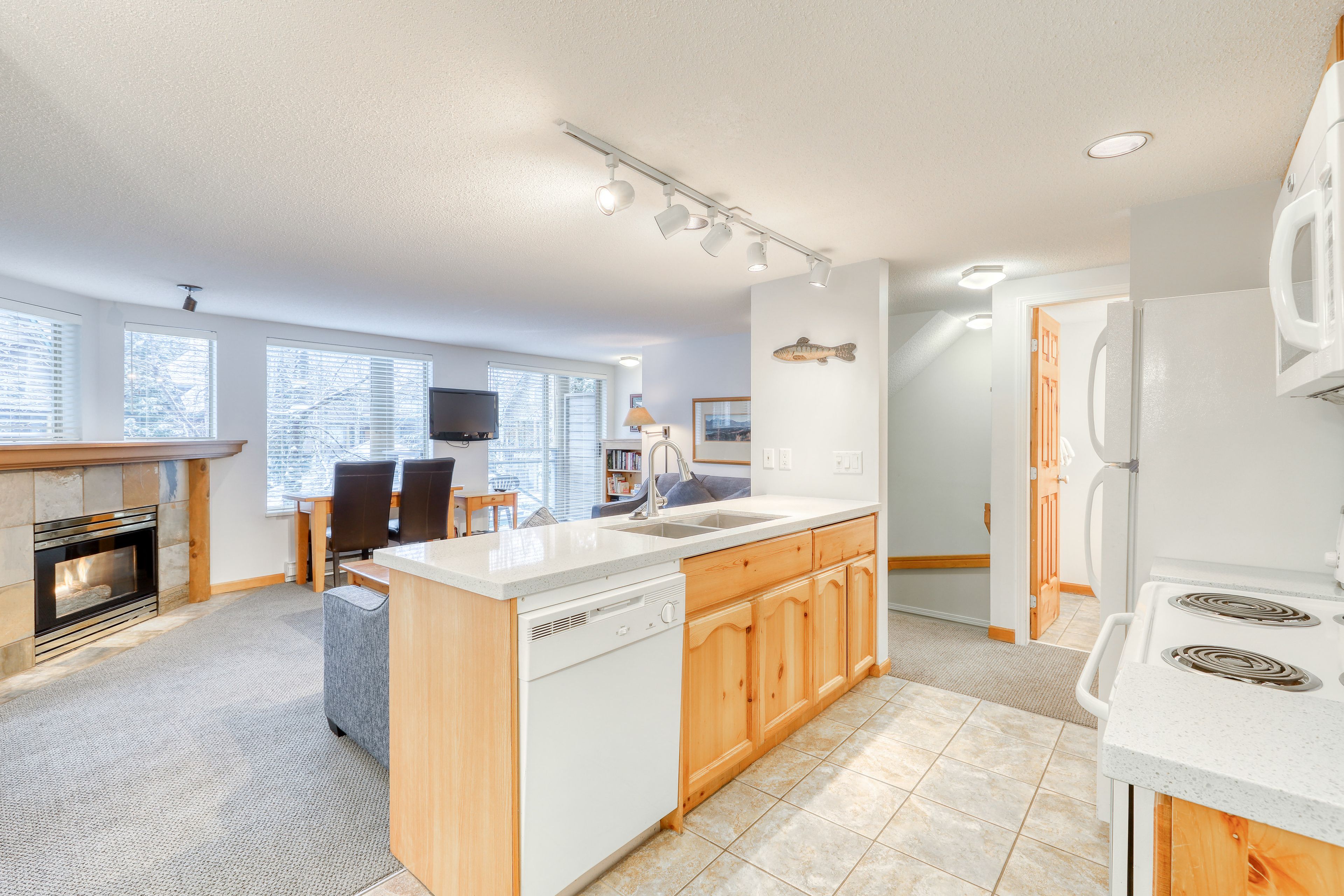 A modern kitchen with a central island, built-in dishwasher, and a stove.