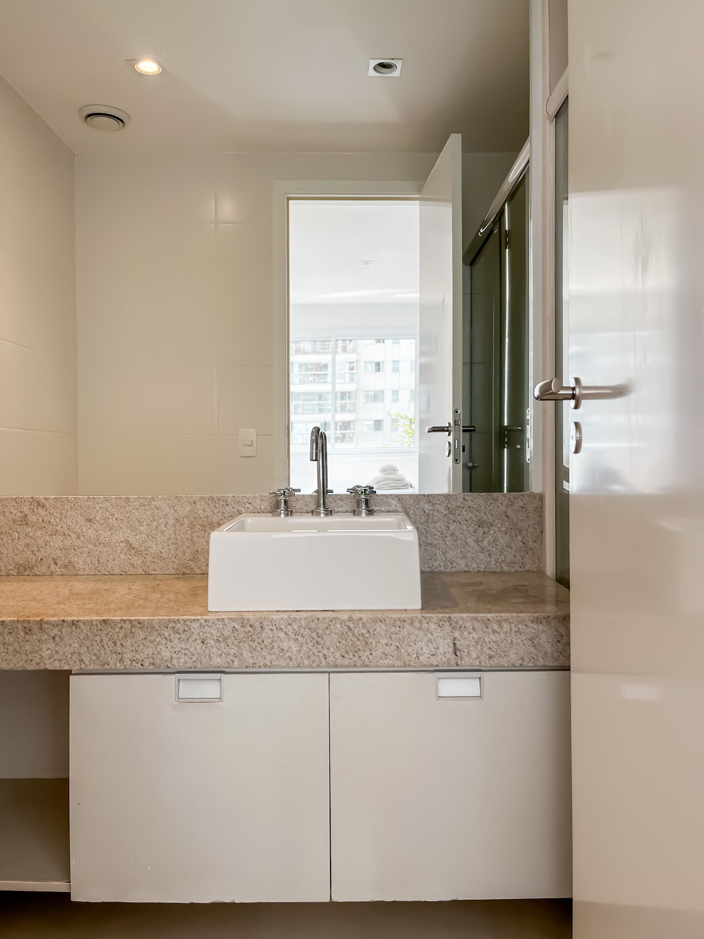 A modern bathroom with a white sink, granite countertop, and a large mirror.