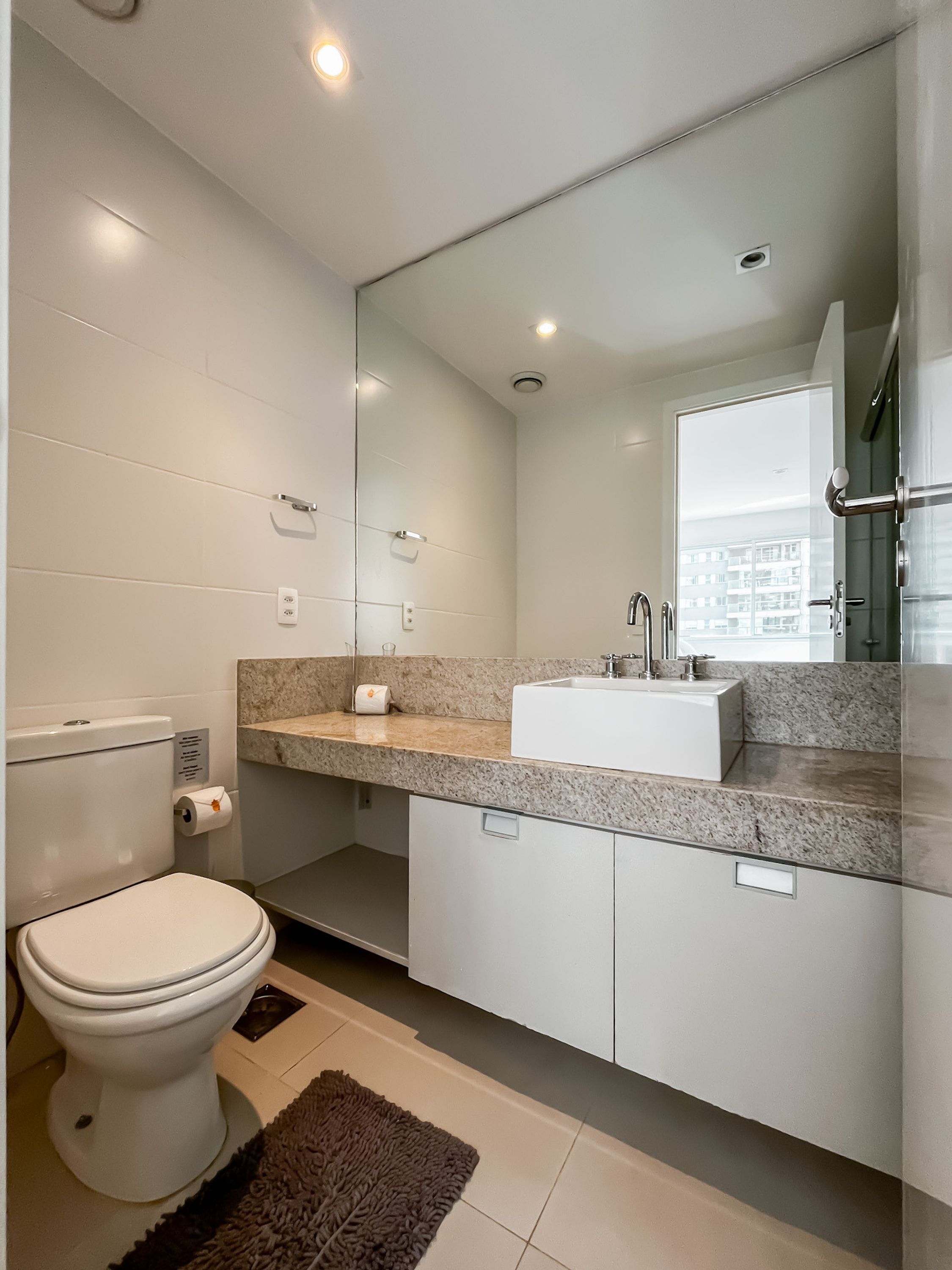 Une salle de bain moderne avec des toilettes, un lavabo et un miroir.