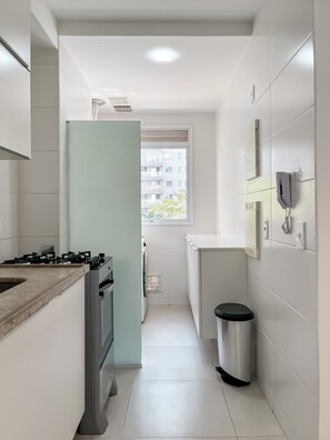 Cozinha moderna com fogão a gás, forno e janela com vista para edifícios.