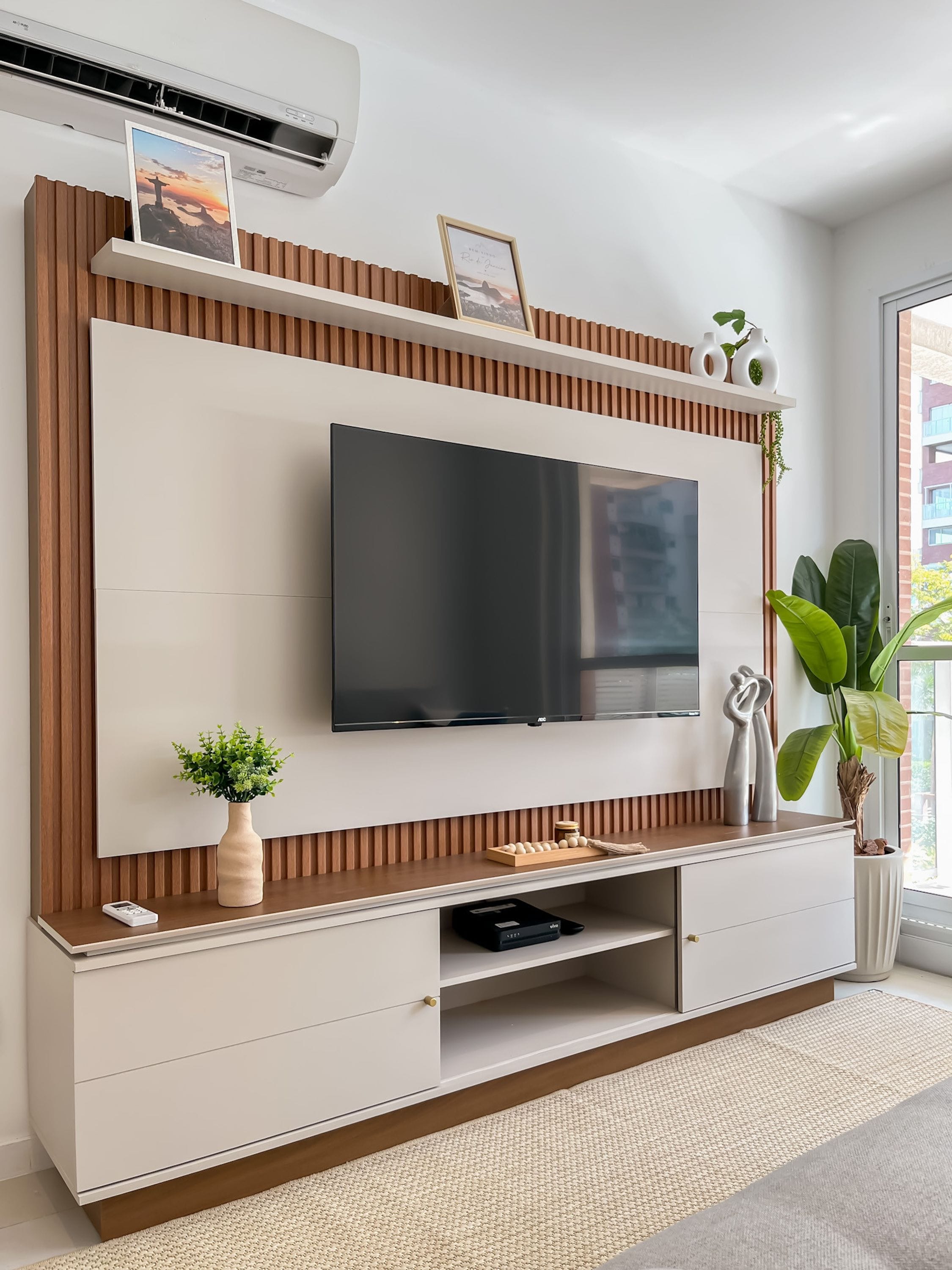 Un mueble moderno de entretenimiento con televisor de pantalla plana, almacenamiento integrado y detalles decorativos.