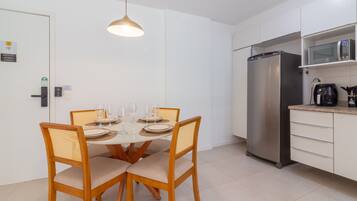 Una cocina moderna con un refrigerador de acero inoxidable, un microondas y una cafetera en la encimera.