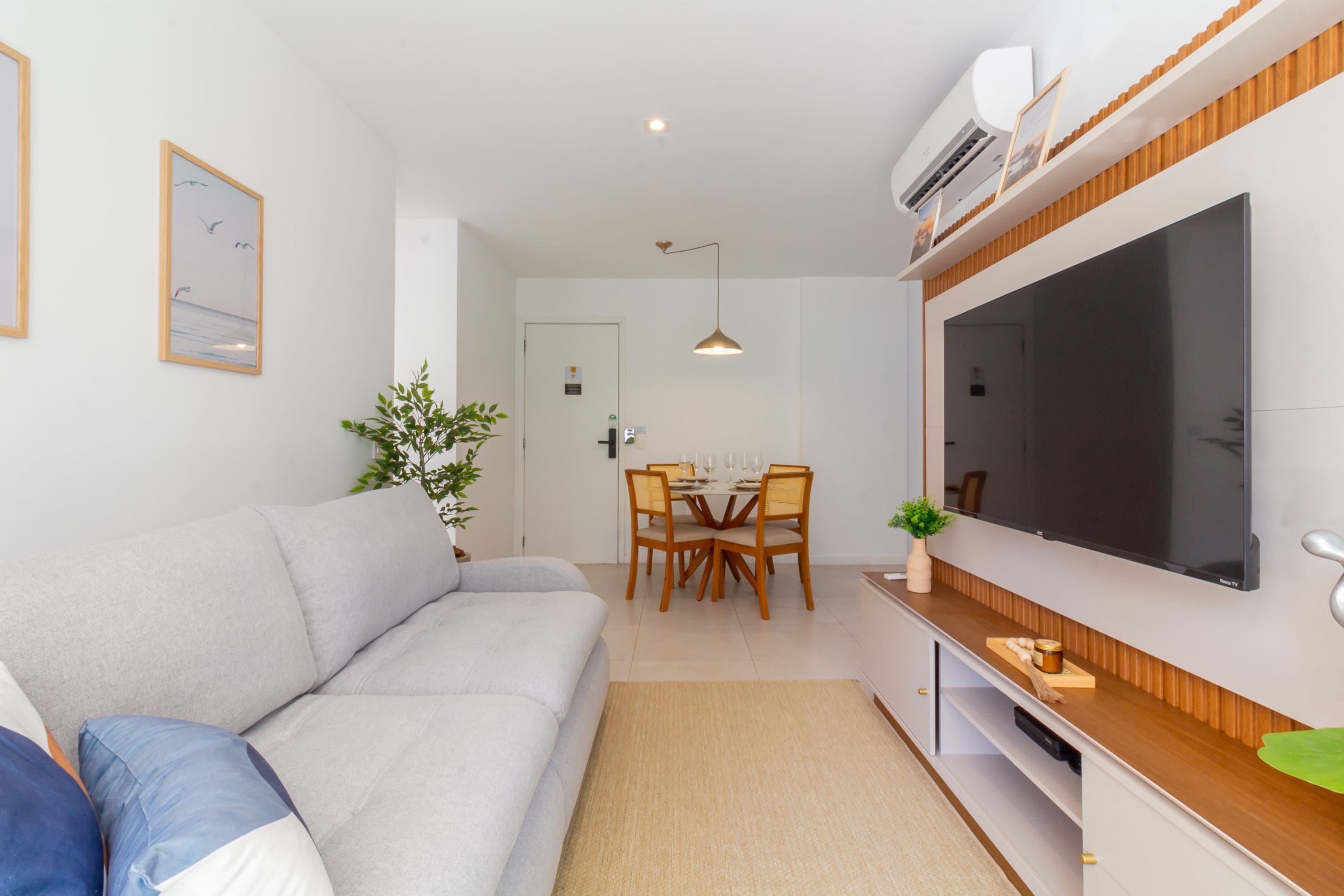 Ein modernes Wohnzimmer mit einer Couch, einem Esstisch, Stühlen und einem Flachbildfernseher.