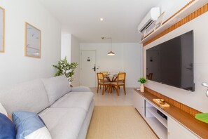 Uma sala de estar moderna com sofá, mesa de jantar, cadeiras e uma TV de tela plana.