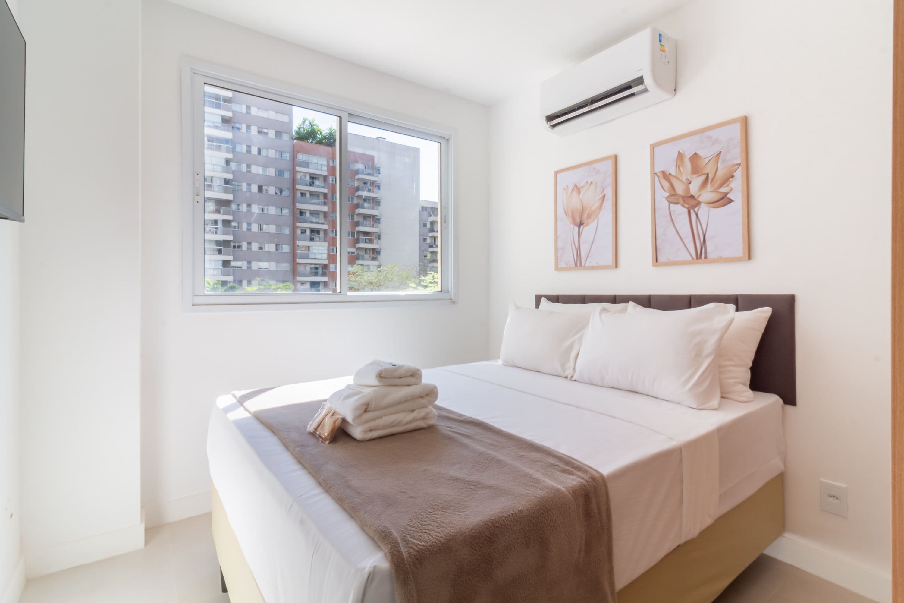 Ein Schlafzimmer mit einem Bett, einem Fenster und zwei Wandklimaanlagen.