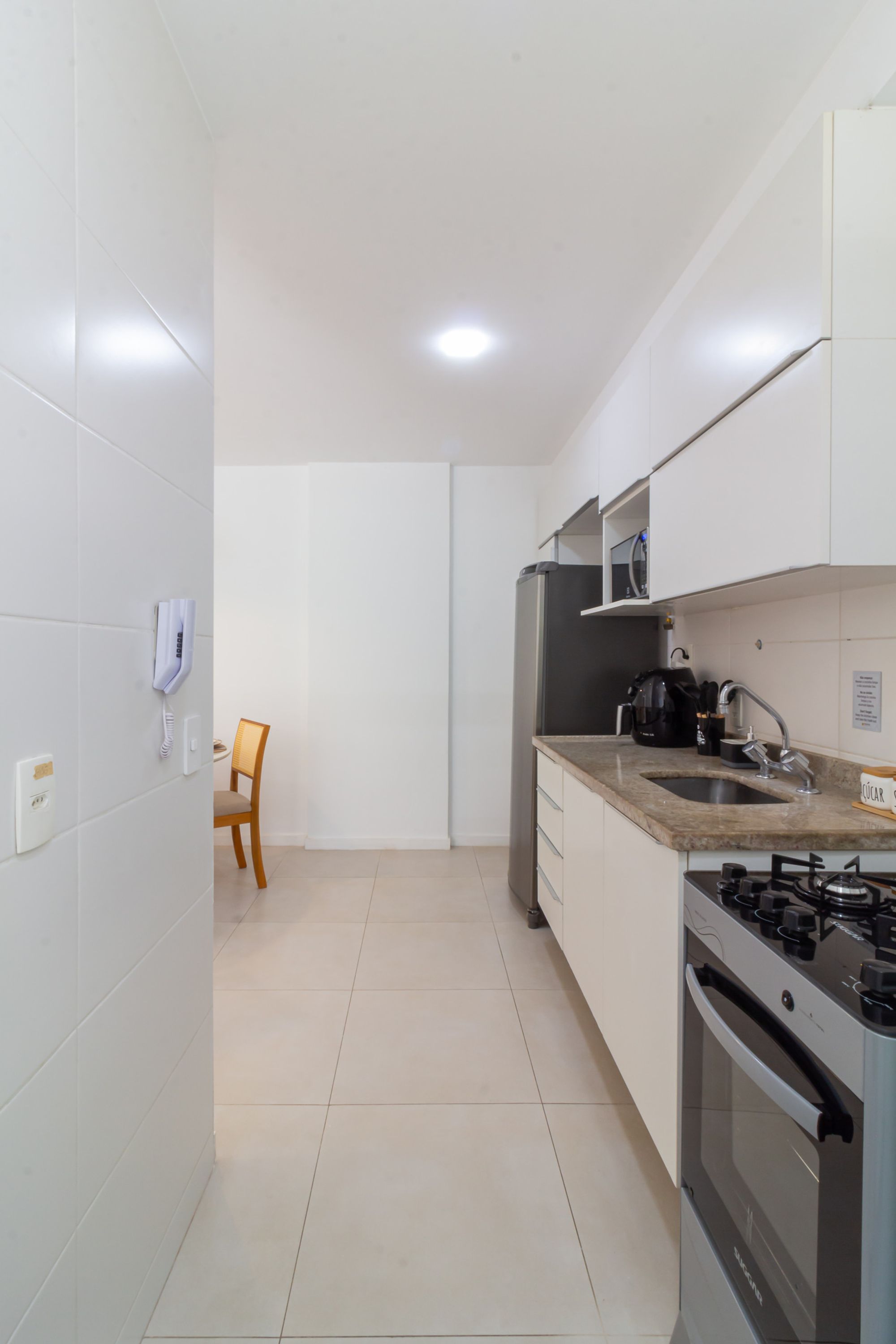 Una cocina moderna con armarios blancos, un refrigerador de acero inoxidable, una estufa a gas y un microondas.