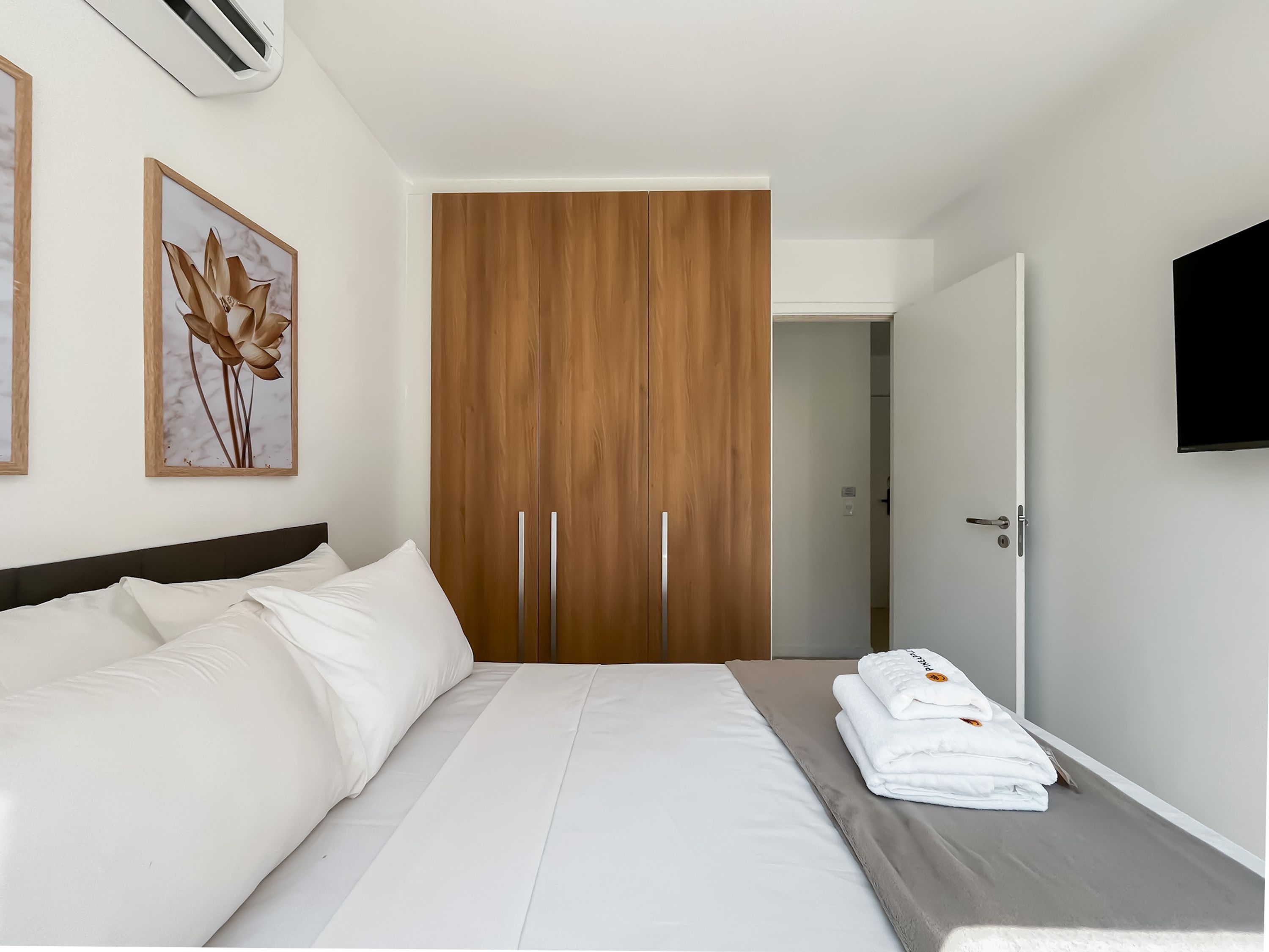 Ein Hotelzimmer mit Bett, einem Kleiderschrank, einem Fernseher und Bildern an der Wand.