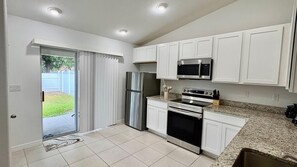 A kitchen with white cabinets, stainless steel appliances, and a granite countertop. - Peaceful 3-bedroom house with AC in charming Palm Coast (Palm Coast)