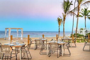 A beachside dining area with tables and chairs, overlooking the ocean. - Romantic get away to Secrets Tides Punta Cana in the Dominican Republic (Playas)