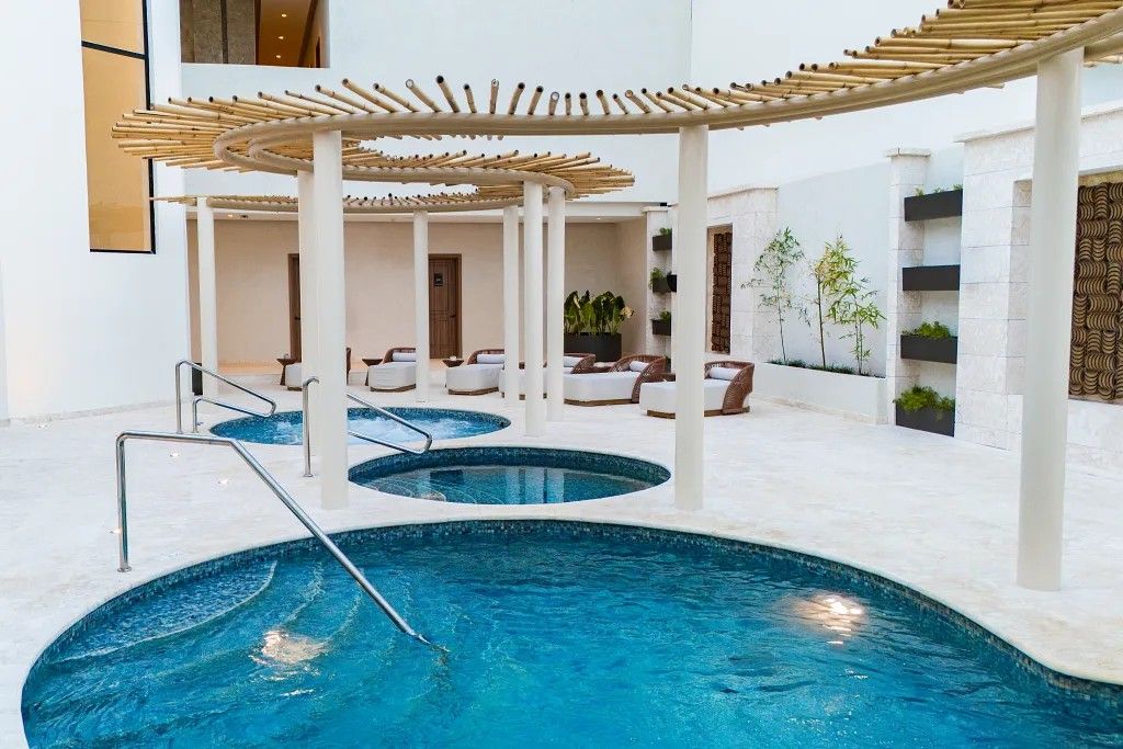 En indendørs swimmingpool med flere niveauer af siddepladser og en pergola i bambus.