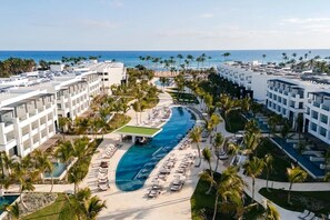A resort with a central swimming pool, multiple balconies, and a beach view. - Romantic get away to Secrets Tides Punta Cana in the Dominican Republic (Playas)