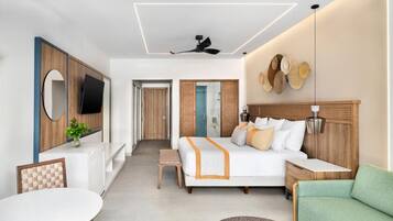Ein modernes Hotelzimmer mit Bett, Schreibtisch, Stuhl, rundem Tisch und Fernseher.