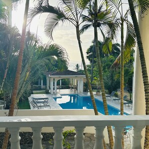 A pool area with a gazebo, palm trees, and lounge chairs. - Enjoyable Beautiful  oceanview first floor  apartment  in charming Cofresi (Cofresi)