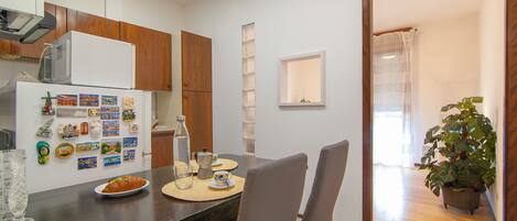 A modern kitchen with wooden cabinets, a refrigerator, and a dining area with a table set for two.