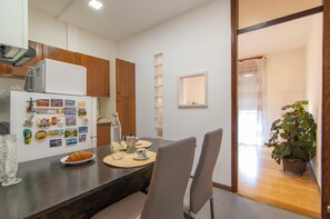 Una cucina moderna con mobili in legno, un frigorifero e un'area pranzo con un tavolo apparecchiato per due persone.