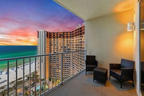 Un balcon avec vue sur un immeuble d’hôtel et une plage.