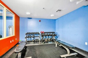 A gym with a blue wall, a bench, and a rack of dumbbells. - Beachfront 2BR+Bunks | Gulf View & Lagoon Pool (Panama City Beach)