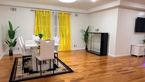 Un coin repas avec une table et des chaises, un meuble noir avec des étagères et une plante en pot.