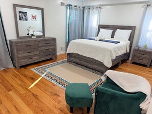 A bedroom with a bed, a dresser, a nightstand, a chair, and a rug.