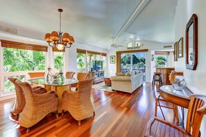 A spacious living area with a dining table, wicker chairs, a sofa, and a ceiling fan. - BEAUTIFUL HAWAIIANA 3/3 TOWNHOUSE WITH AC & MOUNTAIN VIEWS (Princeville)