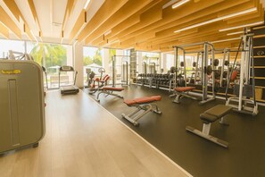 A gym with various exercise equipment, including treadmills, weight machines, and benches. - Luxury Condo in La Amada | Private Beach and Resort (Q.R.)