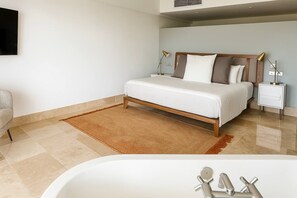 Une chambre à coucher moderne avec un lit, des tables de chevet, une commode, un téléviseur et une baignoire.