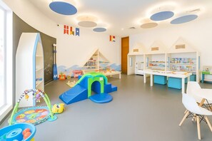 A children's play area with a slide, play tables, and educational toys. - Luxury Condo in La Amada | Private Beach and Resort (Q.R.)