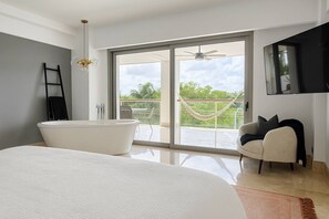 Une chambre moderne avec un grand lit, une baignoire et un balcon offrant une vue agréable.