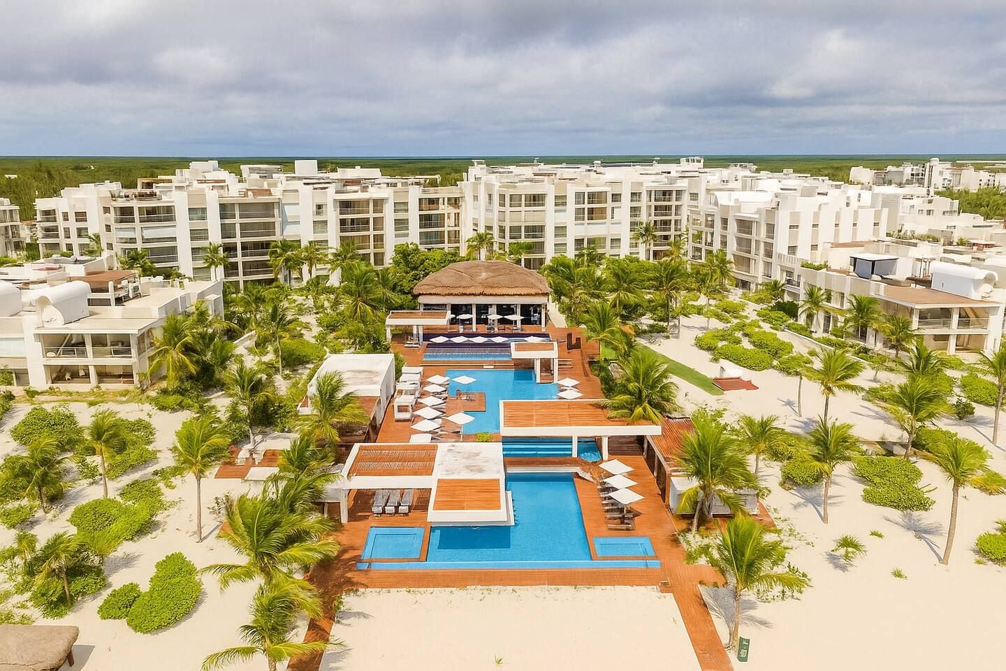 Ein Resort mit einem zentralen Pool, mehreren Gebäuden und Palmen.