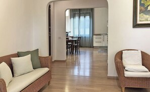 A hallway with a sofa, a wicker chair, and a dining area in the background. - Spacious, bright apartment with parking in the Da Pia neighborhood (Spello)
