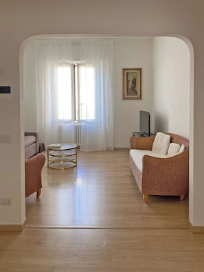 A spacious living room with a sofa, a small table, and a television. - Spacious, bright apartment with parking in the Da Pia neighborhood (Spello)