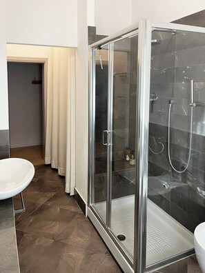 Ein modernes Badezimmer mit einer Duschkabine aus Glas, einem weißen Waschbecken und einer Tür zu einem weiteren Raum.