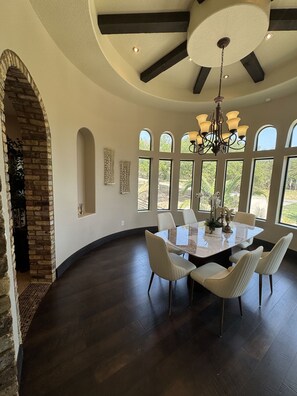 A dining area with a round table, chairs, and a chandelier. - Luxury Hill Country Estate - Sleeps 18 - Perfect for Groups (New Braunfels)