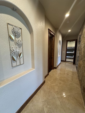 Un couloir agrémenté d’un élément décoratif mural, d’une porte en bois et d’un mur en pierre.