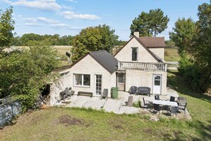 A stone house with a balcony, outdoor seating, and a barbecue area. - Lovely holiday home near Asnæs, Zealand (Asnæs)