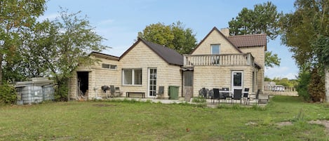A stone house with a balcony, a garage, and outdoor seating.