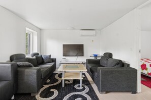 Ett modernt vardagsrum med två grå soffor, ett soffbord och en platt-TV som är monterad på väggen.