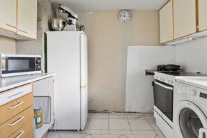 A compact kitchen with a microwave, refrigerator, stove, and washing machine. - Lovely holiday home near Asnæs, Zealand (Asnæs)