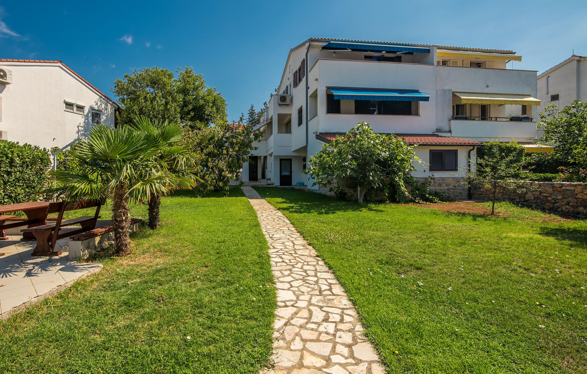 A residential building with a paved pathway leading to the entrance.