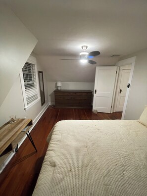 A bedroom with a bed, a dresser, a ceiling fan, and a window with blinds. - Quaint 2-bedroom Cottage Walking Distance to the Beach (Yarmouth)