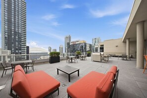 Una terraza en la azotea con mesas al aire libre, vistas del horizonte de la ciudad y un hotel Marriott al fondo.