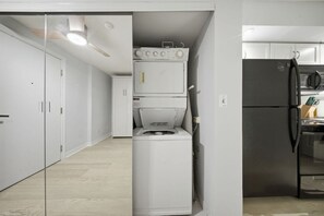 Eine kompakte Küche mit integrierter Waschmaschine und Trockner, einem Kühlschrank und einer Mikrowelle.