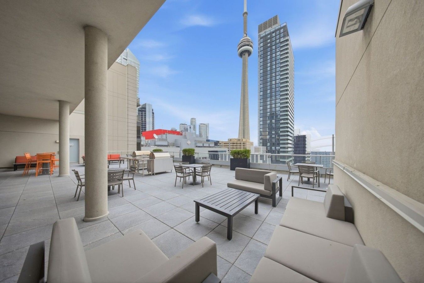 A rooftop terrace with outdoor seating, a view of a city skyline, and a prominent tower.