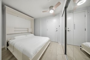 Ein Schlafzimmer mit einem Bett, Deckenventilator, einer Tür und einem Kleiderschrank.